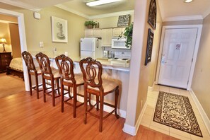 A dining area with wooden chairs and a kitchen in the background.