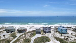 Une propriété située en bord de mer, comprenant plusieurs maisons, une plage de sable et l’océan en toile de fond.