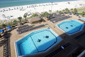 A resort with two large swimming pools, a beach area, and sun loungers.