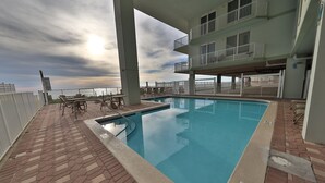 A rooftop pool with a view of the ocean, surrounded by lounge chairs and a covered area. - 1st floor 3br Marisol unit sleeps 8! (Panama City Beach)