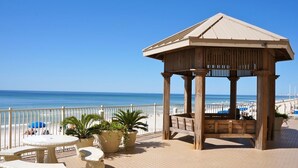 A gazebo with a tiled deck, outdoor seating, and potted plants.