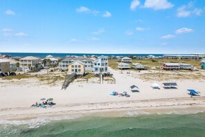 A beachfront property with multiple houses, a sandy beach, and a clear view of the ocean.
