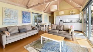Un vaste espace de vie comprenant deux canapés, une table basse et une table à manger. De grandes fenêtres et une cuisine se trouvent à l’arrière-plan.