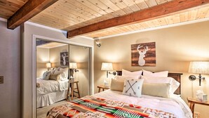 Een slaapkamer met een groot bed, een spiegel en een houten plafond.
