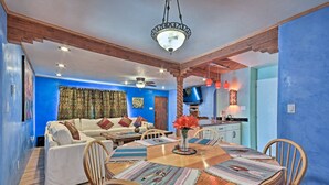Un espace repas comprenant une table ronde en bois, un canapé blanc et des tapis à motifs.