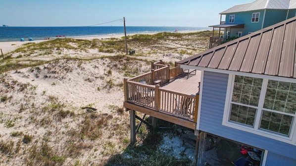 Une maison de plage avec une terrasse en bois donnant sur la plage.