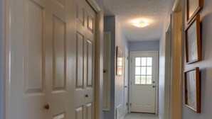 A hallway with white doors, a carpeted floor, and framed pictures on the wall.