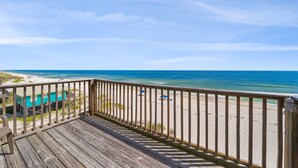 Eine Holzterrasse mit Blick auf Strand und Meer.