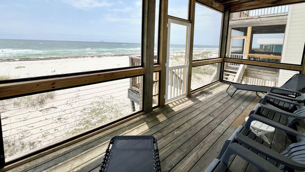 Eine Holzterrasse mit Blick auf Strand und Meer.