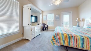 Ein Schlafzimmer mit einem Bett, einem Fernseher, einem Sessel und einem Deckenventilator.