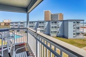 Un balcone con piscina, edifici a più piani e cielo sereno.