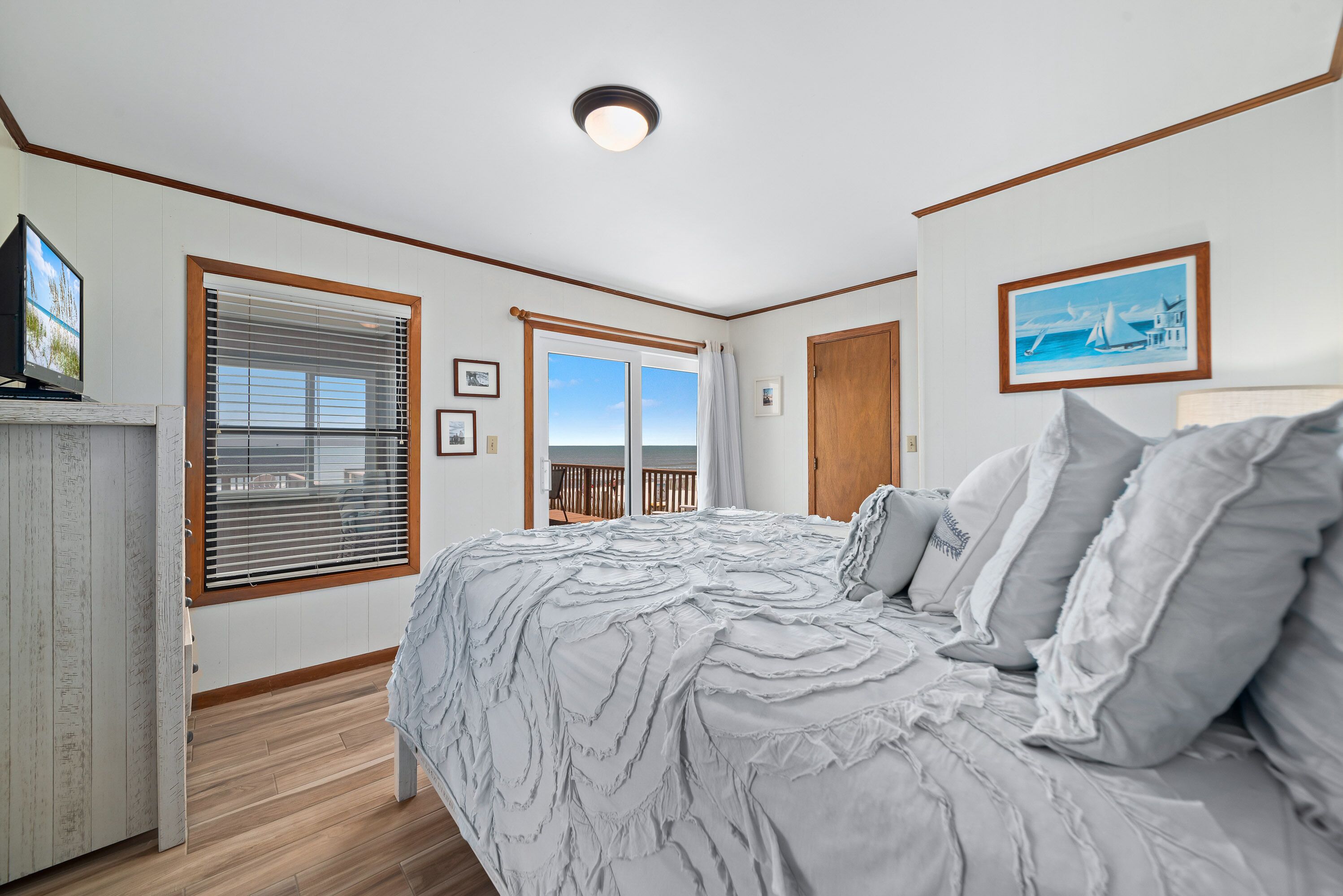 A bedroom with a large bed, a view of the balcony, and a ceiling light.