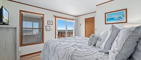 A bedroom with a large bed, a view of the balcony, and a ceiling light.
