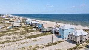 A coastal residential area with houses near the beach, featuring a clear view of the ocean and sandy terrain.
