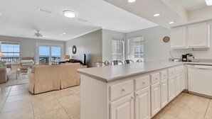 A spacious kitchen with white cabinets, a large island, and a dining area with a view.