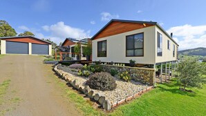 A modern two-story house with a stone foundation and a wooden deck. - Moon River Retreat - Panoramic water views (Gardners Bay)