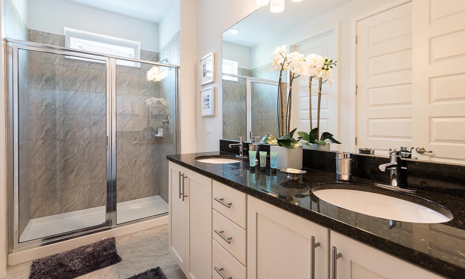 A modern bathroom with a glass-enclosed shower, two sinks, and a large mirror.