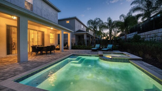 A swimming pool with a hot tub, outdoor seating, and a patio area. - Modern 4 Bedroom Home with Game Room in Encore Resort (Kissimmee)
