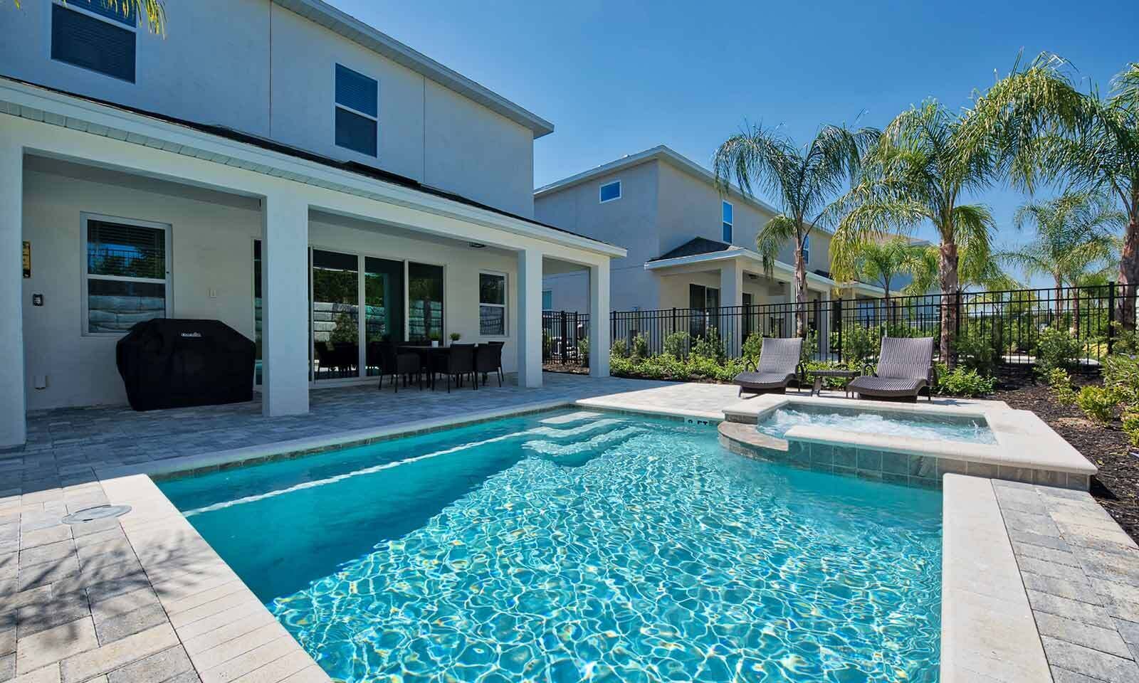 A swimming pool with a patio area, outdoor seating, and a covered section.