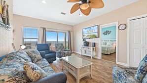 A spacious living room with a large ceiling fan, a sofa set, a coffee table, and a view of the balcony. - Amazing 5 Bedroom Gulf Front home with private pool just steps from the Gulf (Gulf Shores)