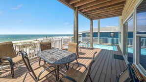 A wooden deck with a table and chairs, overlooking a beach and a pool. - Amazing 5 Bedroom Gulf Front home with private pool just steps from the Gulf (Gulf Shores)