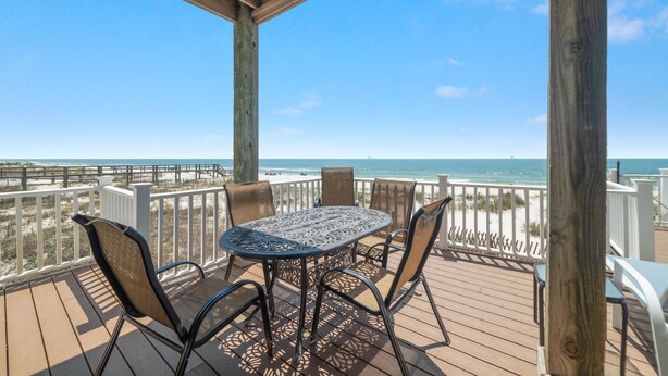 A wooden deck with a round table and chairs, overlooking a beach and ocean. - Amazing 5 Bedroom Gulf Front home with private pool just steps from the Gulf (Gulf Shores)