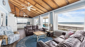 A room with a wooden ceiling, a beach view, a kitchen, and a seating area with a coffee table. - AFFORDABLE and Charming 2 Bedroom Gulf Front Home, Sleeps 6 (Gulf Shores)