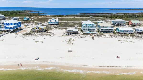 A coastal area with beachfront properties, including houses and a building with a pool. - AFFORDABLE and Charming 2 Bedroom Gulf Front Home, Sleeps 6 (Gulf Shores)