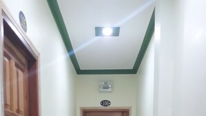 A hallway with a wooden door on the left, a green mat at the entrance, and a sign above the door indicating room number 106.