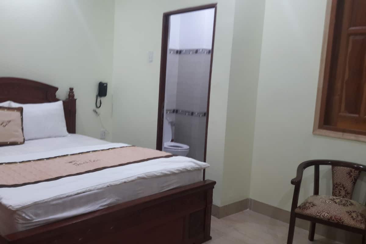 A bedroom with a wooden bed, a bedside table, a chair, and a mirror.