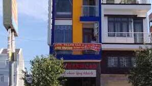 A multi-story building with a blue and yellow facade, a visible ground-floor entrance, and a signboard.