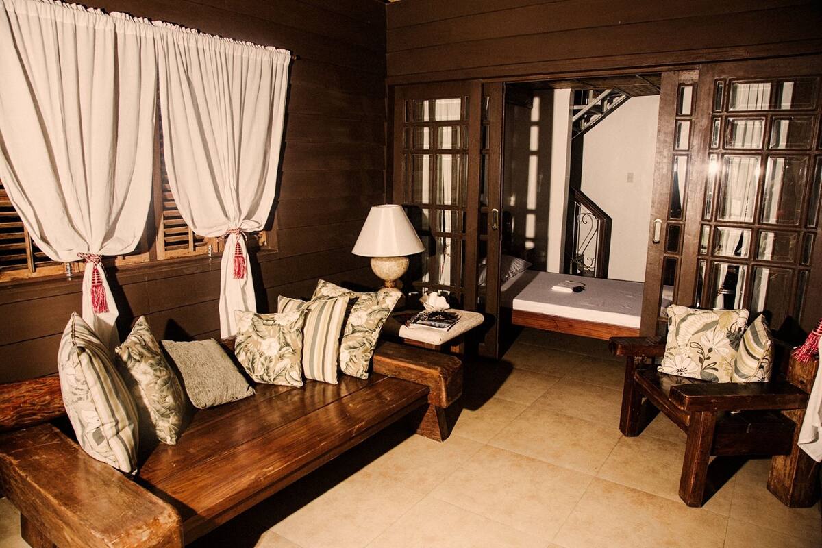 A cozy room with a wooden bench, a small table with a lamp, and a bench with cushions.