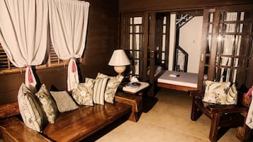 A cozy room with a wooden bench, a small table with a lamp, and a bench with cushions.