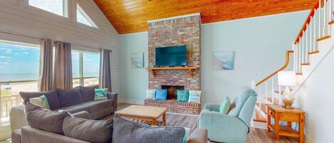 A spacious living room with a fireplace, a sofa, a chair, and a TV mounted on a brick wall.