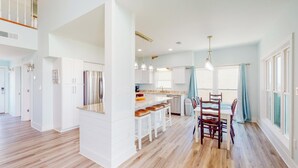 Una cocina amplia con una isla central, muebles blancos y piso de madera.