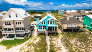 Una propiedad frente a la playa con una casa azul destacada, que cuenta con un balcón y una terraza de madera.