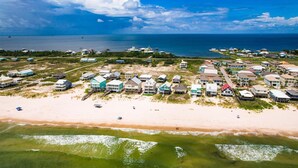 Vista aérea de una zona residencial costera con casas cerca de una playa de arena y el océano.