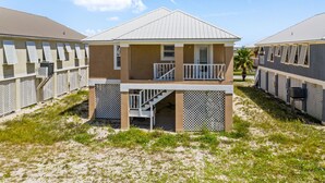 A beachfront hotel with a balcony, a covered outdoor area, and a palm tree. - Affordable Renovated 3 Bd/2 Ba home steps from the beach with pool/tennis access (Gulf Shores)