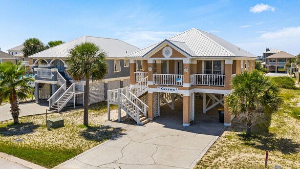 A beachfront hotel with a covered walkway, palm trees, and a clear sky. - Affordable Renovated 3 Bd/2 Ba home steps from the beach with pool/tennis access (Gulf Shores)