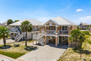 A beachfront hotel with a covered walkway, palm trees, and a clear sky. - Affordable Renovated 3 Bd/2 Ba home steps from the beach with pool/tennis access (Gulf Shores)