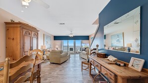 Amplia sala de estar con una mesa de comedor de madera, dos sofás y un ventanal con vistas al exterior.