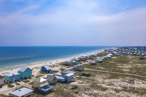 A coastal area with a row of houses along the beach, some with elevated structures.