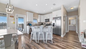 Une cuisine moderne avec des armoires blanches, des appareils en acier inoxydable et un plancher en bois.