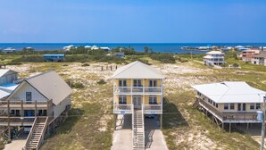 Il s’agit d’une propriété située en bord de mer, comprenant plusieurs bâtiments, dont une imposante maison à deux étages dotée d’un balcon et d’un escalier menant à l’entrée.
