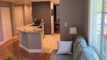 A modern living room with a gray sofa, a glass coffee table, and a ceiling fan.