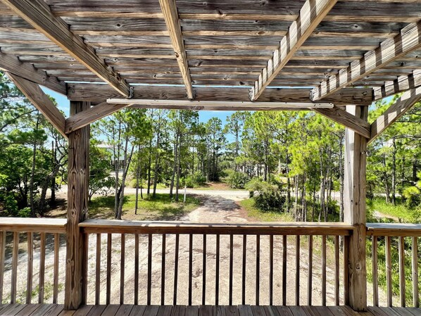 A wooden pergola structure with a view of a forested area.