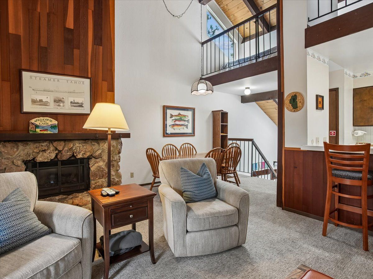 A cozy living room with a fireplace, comfortable seating, and a staircase leading to an upper level.