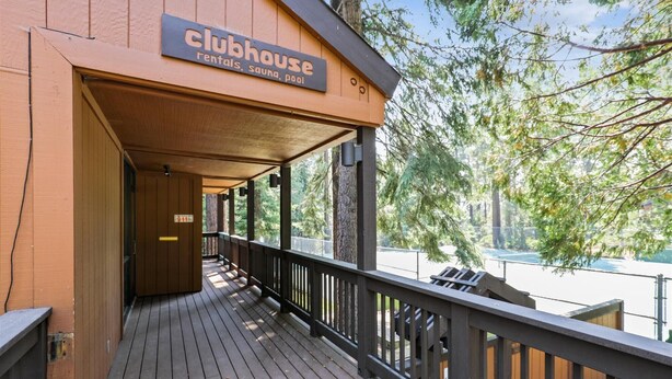 Una casa de campo de madera con un porche cubierto y un cartel que indica que ofrece alquileres, sauna y piscina.