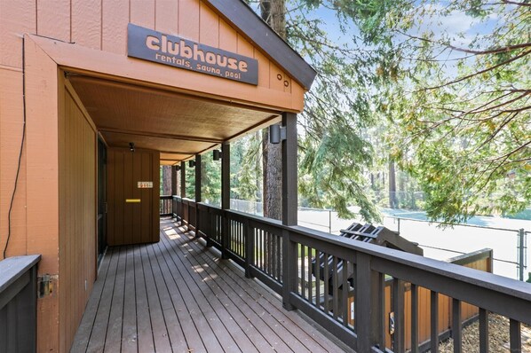 Una casa de campo de madera con un porche cubierto y un cartel que indica que ofrece alquileres, sauna y piscina.