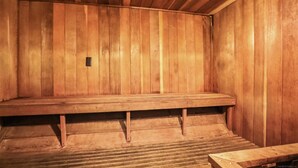 Una sauna de madera con un banco y una pequeña mesa.